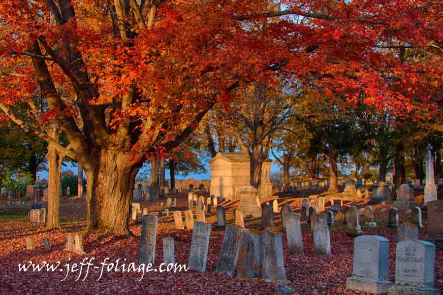 Fall foliage shot in Dover cemetery in New Hampshire. The late afternoon sun reaches out across the cemetery stones with the final suns rays.