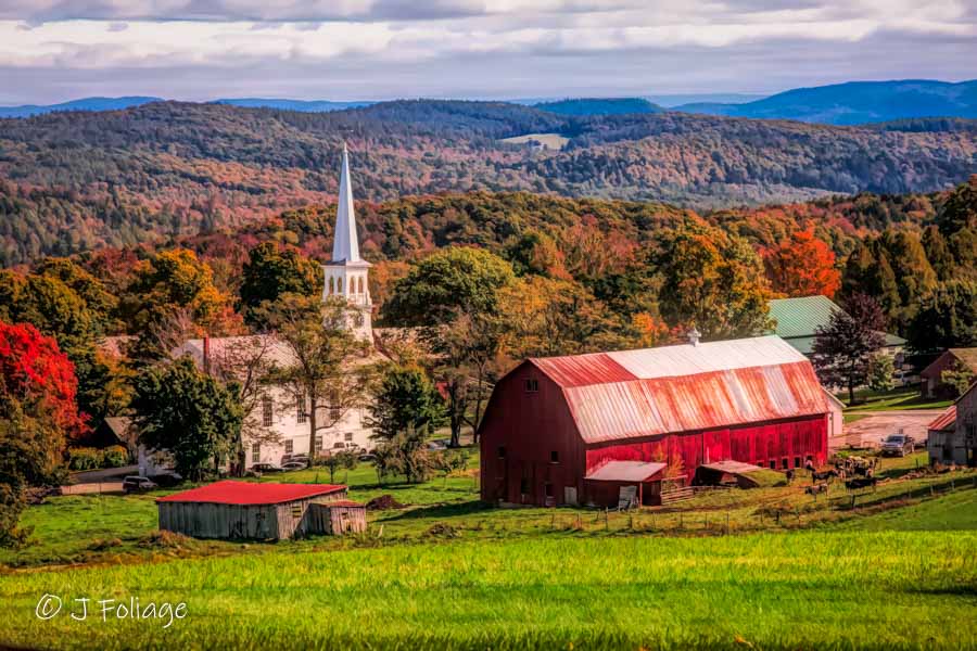 A fall day with a view of the church and red farm buildings in Peacham Vermont
