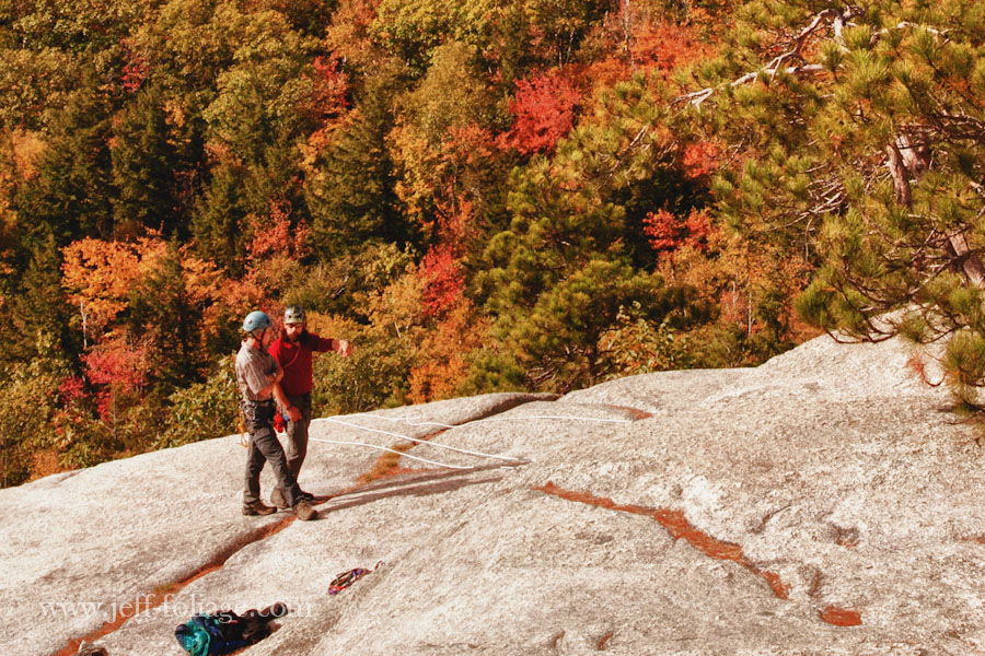 two hikers prepare to repel down through the Fall foliage on Cathedral ledge
