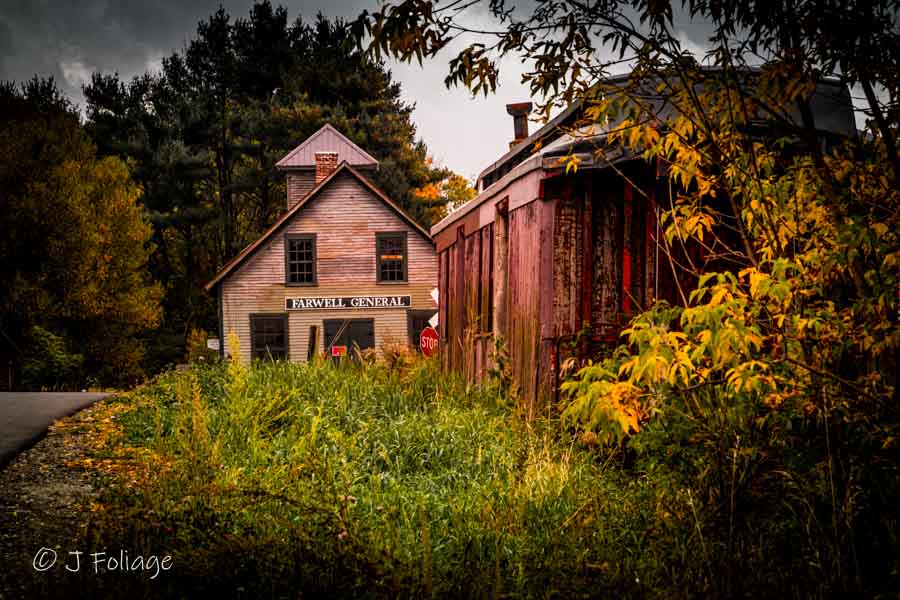 An old red caboose next to the farwell general store. the red caboose is weathered and rustic. The white paint on the store is peeling