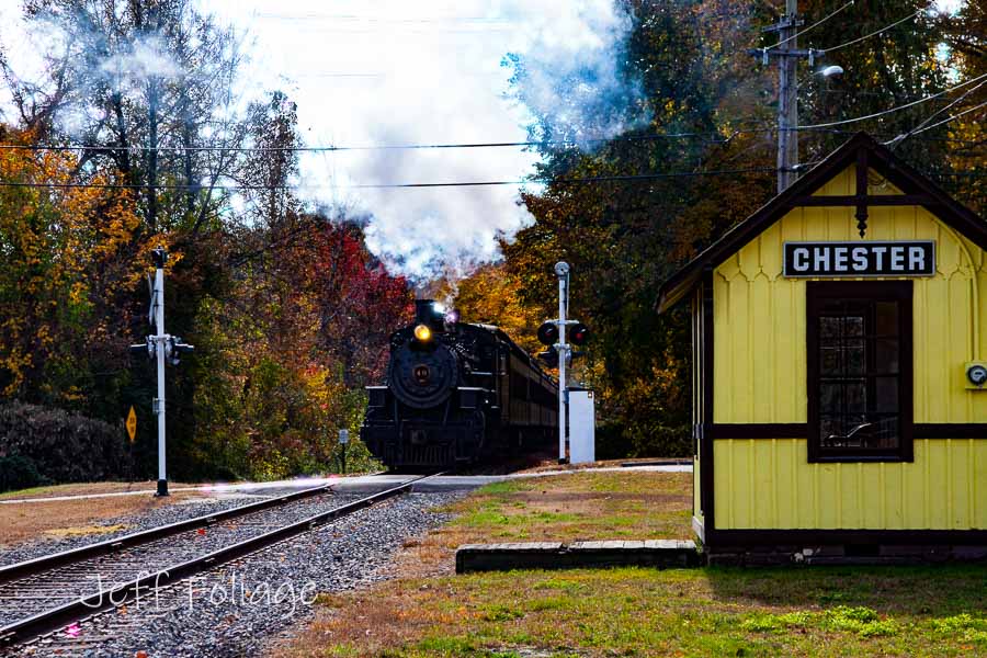 Steam locomotive coming through the fall colors pulling passenger cars