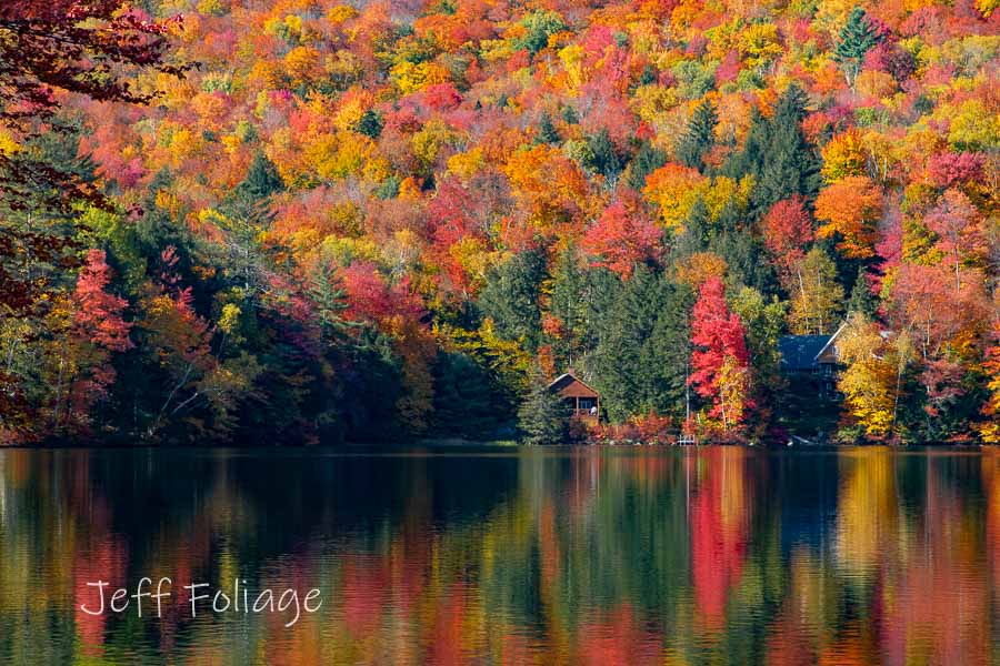 Peak fall colors surrounding Mirror Lake in Thornton New Hampshire