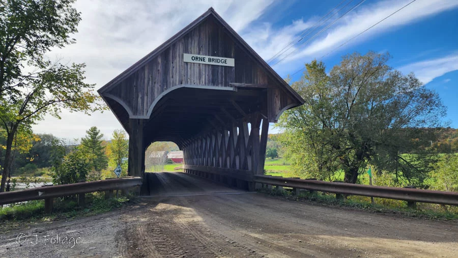 Orne-Coventry covered bridge on an early fall fall day with blue skies and puffy white clouds