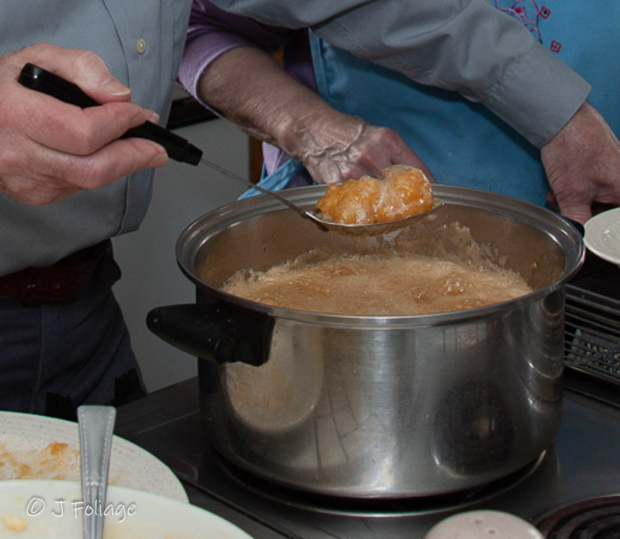 Maple dumplings being scooped out of boiling maple syrup