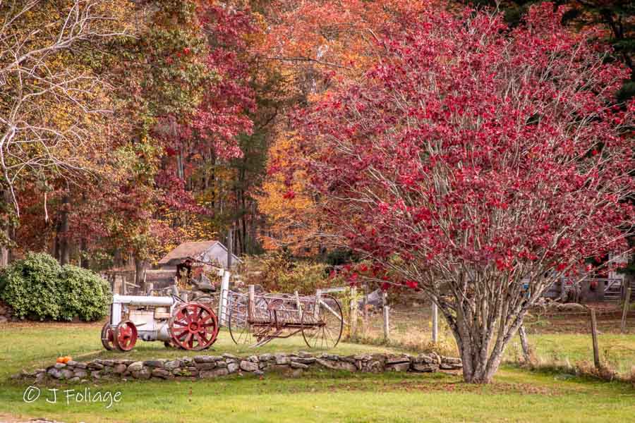 An old tractor and hay tedder sit in a Connecticut yard