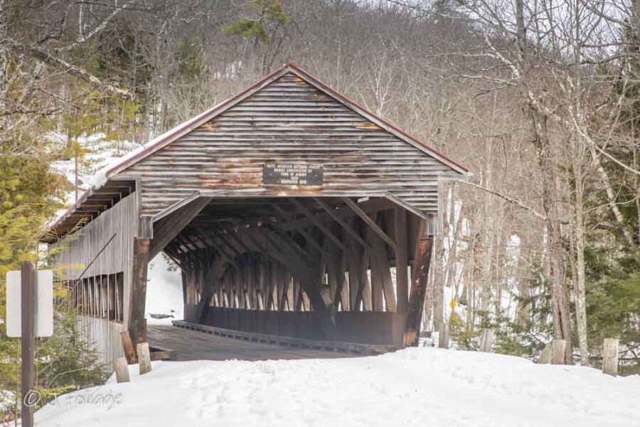 Albany Covered Bridge (Snowy): A side-view of the wooden Albany Covered Bridge with deep snowbanks in the foreground and the icy Swift River below.