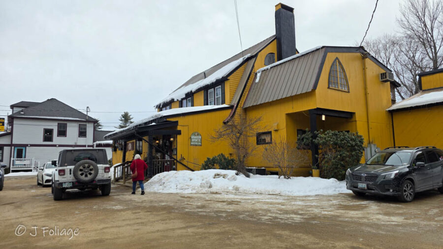 Exterior: The bright yellow exterior of May Kelly’s Cottage Bar and Restaurant in North Conway, surrounded by winter snow.